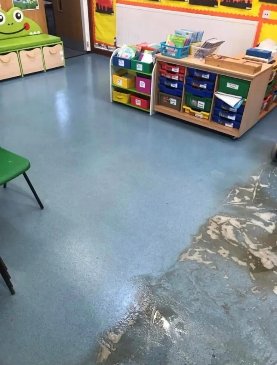 A speckled blue hard floor in a nursery room being cleaned, with lifted soil visible on the wet surface beside storage units