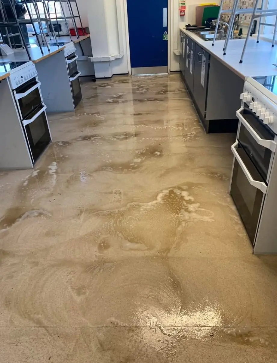 A kitchen hard floor part way through cleaning, with dirty water and lifted soil pooled on the surface ready to be extracted